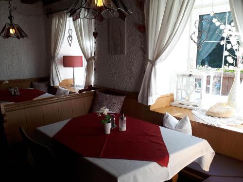布伦纳山口格里斯Gasthaus Vinaders的一间设有红色和白色桌子及窗户的用餐室