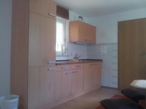 博恩FeWo1的厨房配有木制橱柜、水槽和窗户。