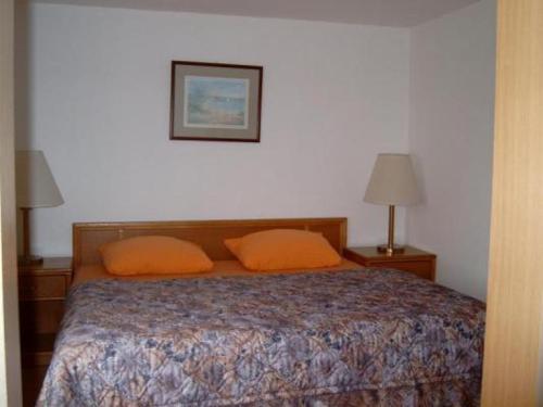 博恩FeWo1的一间卧室配有带两个橙色枕头的床