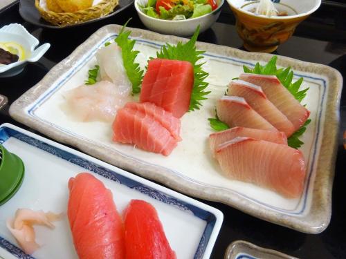 胜浦市龟之井民宿宾馆的一张桌子,上面放着两盘食物,有不同种类的鱼