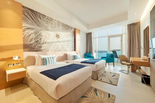 迪拜Royal Central Hotel and Resort The Palm的酒店客房配有两张床和一张书桌