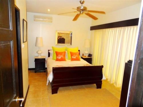 布里奇敦Brownes Condominium 2的一间卧室配有带橙色和黄色枕头的床