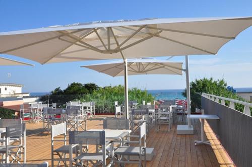 托雷拉皮罗Hotel Intervallo的一个带桌椅的白色遮阳伞庭院。