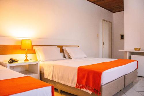 阿拉卡茹Hotel Terra do Sol的酒店客房带两张床,带橙色和白色的床单。