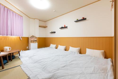 泉佐野ABC民宿的一张大白色的床,位于带桌子的房间