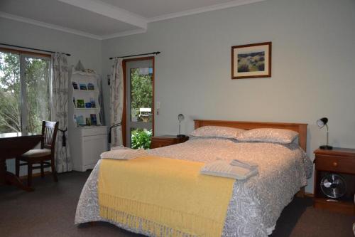 Portobello树顶膳宿旅馆的一间卧室配有一张床、一张桌子和一个窗户。