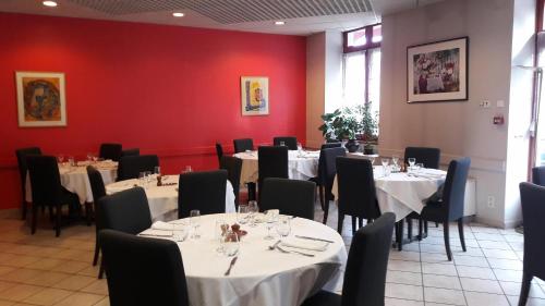 隆勒索涅Logis Hotel du Parc-Restaurant - Le Rouget de Lisle的一间设有桌椅和红色墙壁的餐厅