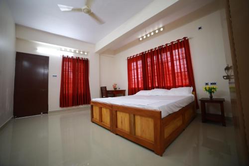 特里凡得琅Indeevaram Residency的一间卧室配有一张带红色窗帘的大床
