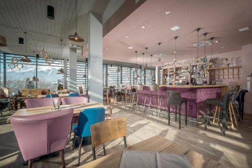 蒂罗尔州圣约翰Cubo Sport & Art Hotel的一间设有紫色椅子的餐厅和一间酒吧