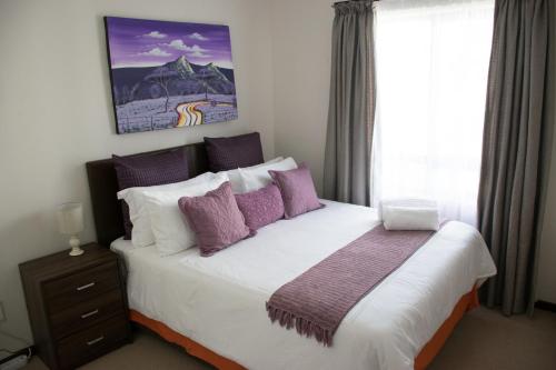 鲁德普特Luxury 2 Bedroom Lifestyle Apartment in Golf Estate的一间卧室配有一张带紫色枕头的大床