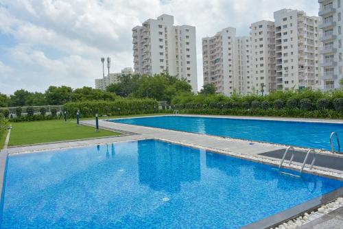 艾哈迈达巴德LE Chalet - Serviced Luxury Condominium的一个大型蓝色游泳池,其背后是高大的建筑