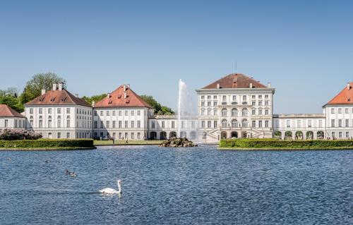 慕尼黑宁芬堡斯加罗斯兰蒙酒店的在楼房前的水中游泳的天鹅