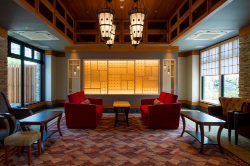 云仙市云仙九州酒店的大堂设有红色的椅子和桌子以及窗户。