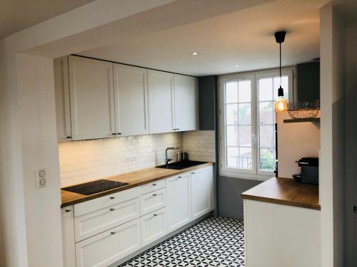 梅尔维尔弗朗瑟维尔普拉格Bel Appartement vue mer的厨房配有白色橱柜和黑白瓷砖地板。