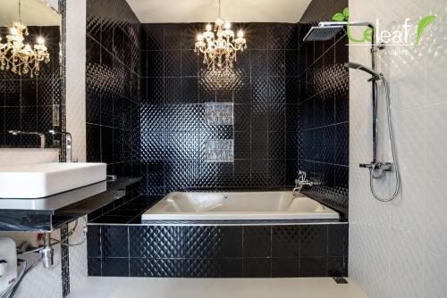 华欣Le Leaf Valley Hua Hin 29的黑色瓷砖浴室设有浴缸和水槽