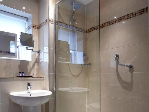 利明顿Macdonald Elmers Court Hotel的一间带玻璃淋浴和水槽的浴室