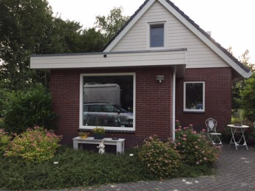 德拉赫滕B & B genieten bij Groen的一座红砖小房子,配有桌子和窗户