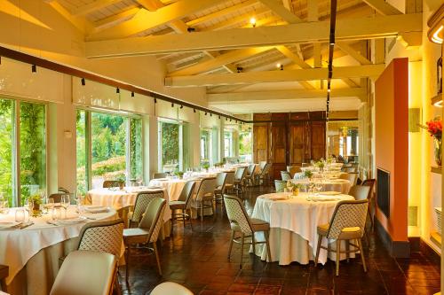蒙希亚Hotel Palacio Urgoiti的餐厅设有白色的桌椅和窗户。