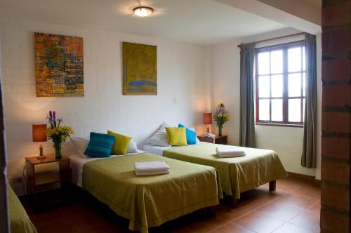 利马卡萨代巴拉巴尔酒店的一间卧室配有两张带黄色和蓝色枕头的床
