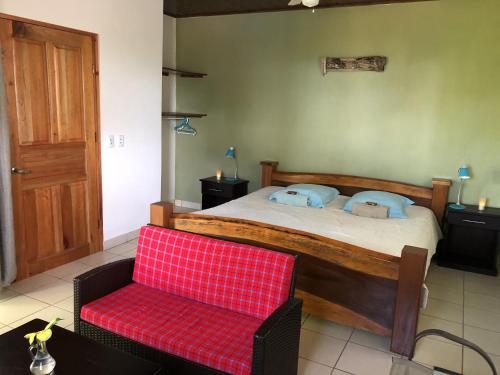 多米尼克Casa del Toucan的一间卧室配有一张大床和一张红色椅子