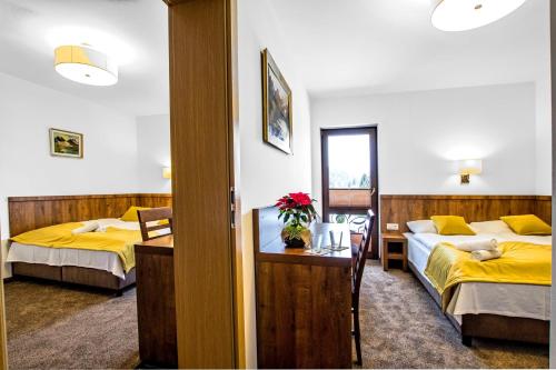 恰萨纳格拉Dworek Nad Białką的酒店客房,设有两张床和一张鲜花桌。