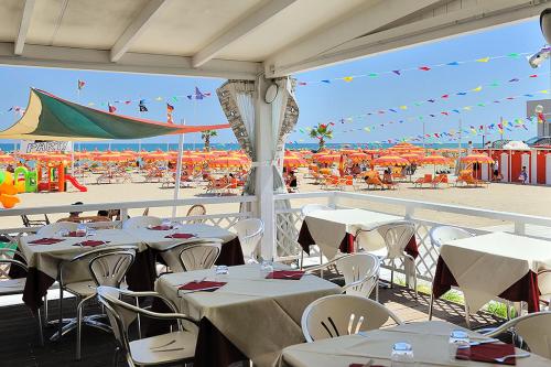 里米尼卡瓦露西奥圣马力诺住宅酒店的一间带桌椅的餐厅以及海滩