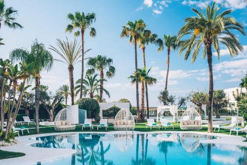 马贝拉Iberostar Selection Marbella Coral Beach的一座棕榈树和白色椅子的游泳池