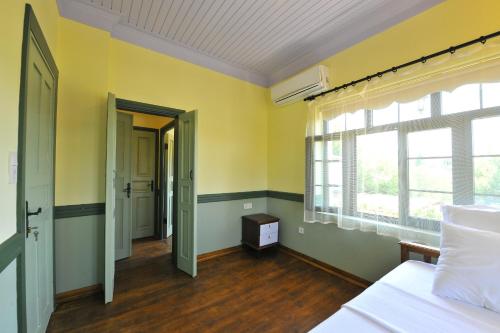 格克切达镇Petrino Gökçeada Hotel&Kitchen的卧室拥有黄色的墙壁和一张床及窗户