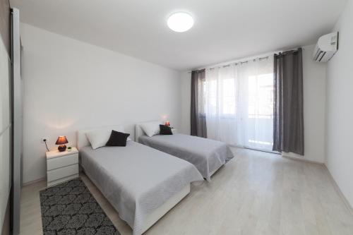扎达尔Apartman Bordura的一间白色卧室,配有两张床和窗户
