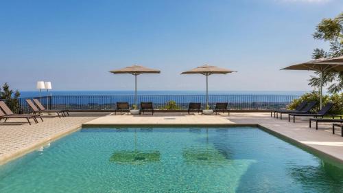 皮耶迪蒙泰埃特内奥故事餐厅及套房度假酒店的一个带椅子和遮阳伞的游泳池以及大海