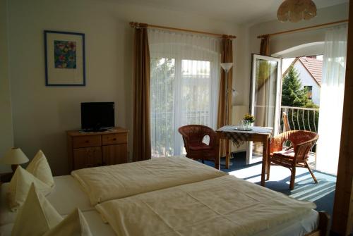 奥斯特巴德·哥伦瓦尔德克旅馆的一间卧室配有一张床铺和一张桌子,并设有一个阳台