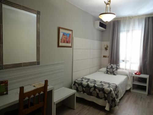 卡塞雷斯洛斯那然约斯酒店的一间卧室配有一张床、一张桌子和一个窗户。