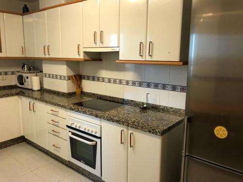 里瓦德奥El piso de Carlos的厨房配有白色橱柜和不锈钢冰箱