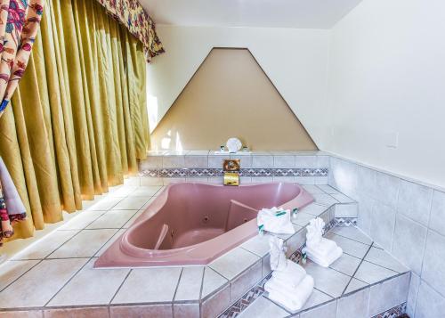 长滩长滩哇卡班德客栈的设有带粉红色浴缸的浴室和天花板