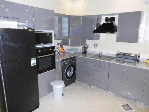 艾因苏赫纳Three-Bedroom Apartment at Louly Beach Resort的厨房配有黑色冰箱和洗碗机。