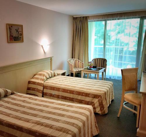 卡瓦尔纳Hotel & SPA Otdih的酒店客房带两张床和一张桌子以及椅子。