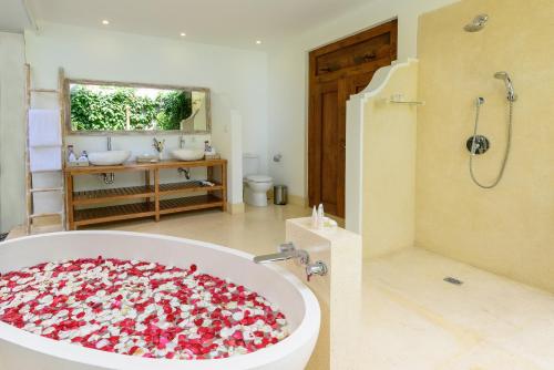 塞米亚克橡胶树别墅的浴室配有鲜花盛开的浴缸。