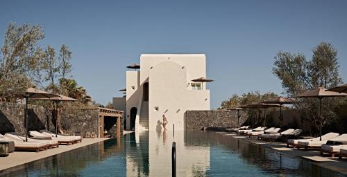 佩里沃罗Istoria, a Member of Design Hotels的一个带游泳池和椅子的度假胜地和一座建筑