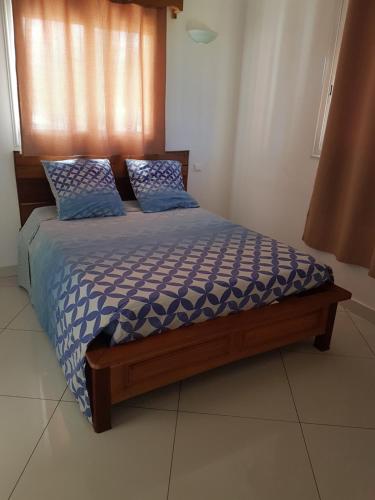 阿姆巴托洛阿卡Villa Violette的一间卧室配有一张带蓝色棉被和枕头的床