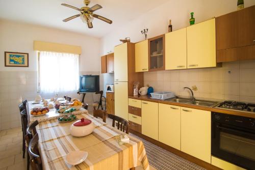 菲乌梅夫雷多迪西奇利亚B&B Casa Paolo的一间带餐桌的厨房和一间带黄色橱柜的厨房