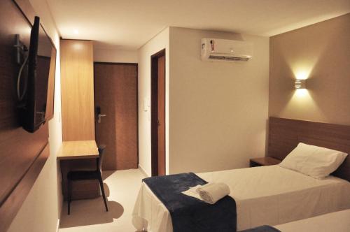戈亚尼亚Rainha Hotel的小酒店客房配有一张床和一把椅子