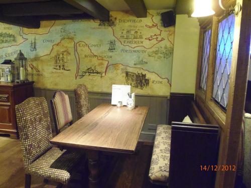 考斯Fountain Inn by Greene King Inns的墙上有地图的木桌和椅子