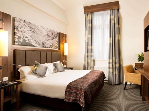 达灵顿达灵顿国王美居酒店的配有一张床和一张书桌的酒店客房