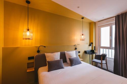 巴黎小型舒适酒店的一间卧室配有一张黄色墙壁和两个灯的床