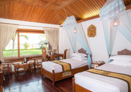 TaungooKMA Kaytumadi Hotel的一间卧室设有两张床、一张桌子和一个窗口