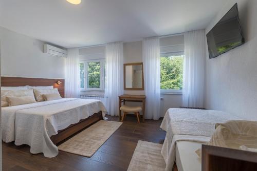 普利特维采湖Up27 Suites Plitvice的一间卧室设有两张床、一台电视和两个窗户。