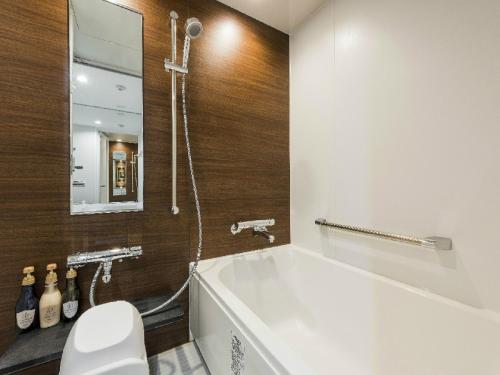 札幌MYSTAYS 札幌 Aspen 酒店的带浴缸、卫生间和镜子的浴室