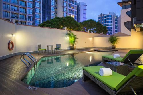 新加坡Park Avenue Robertson的大楼内一个带椅子和桌子的游泳池