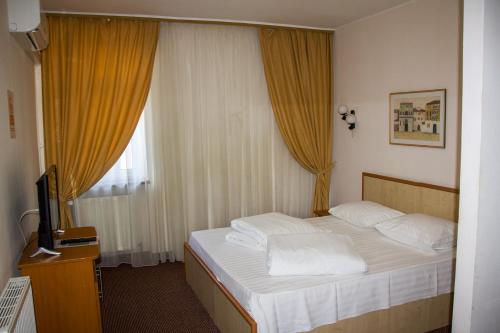 雅西HOTEL T23 srl的一间卧室配有一张带白色枕头的床和电视。