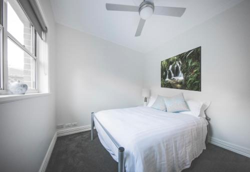 科夫斯港蒂歌斯比奇度假屋的白色卧室配有床和吊扇